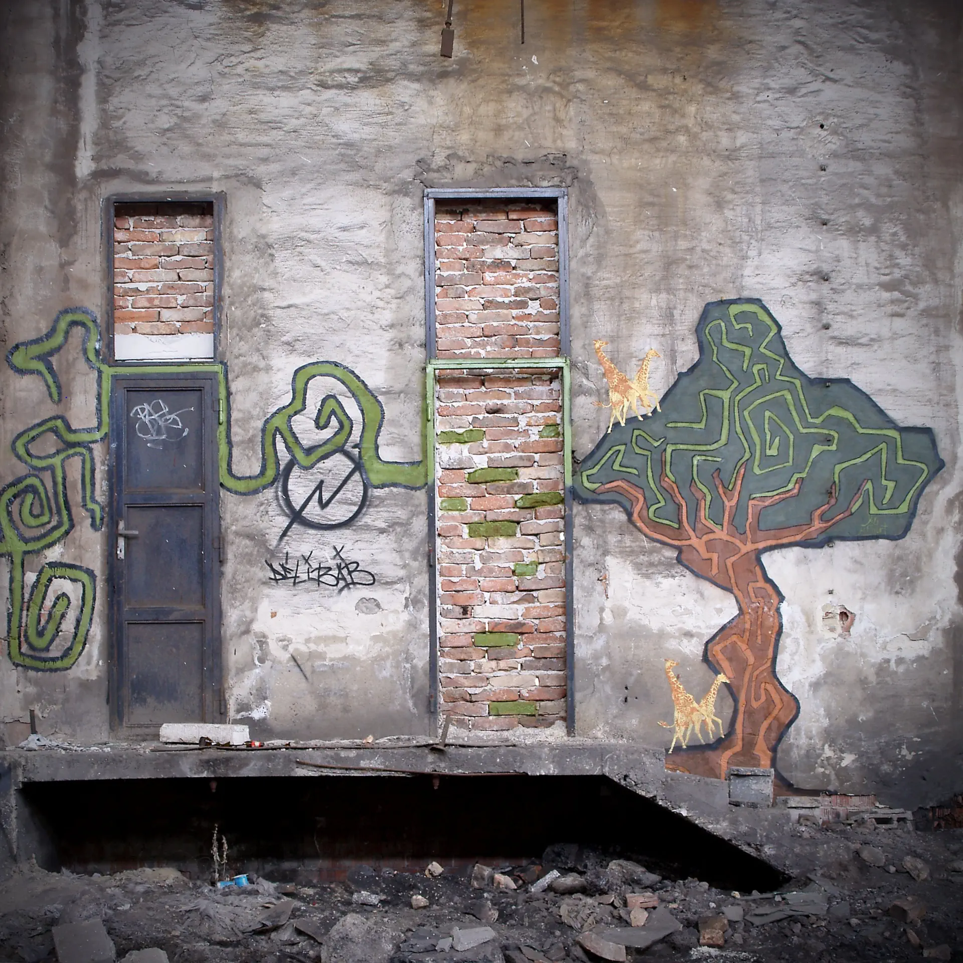 Graffiti egy romos felületen: fa, rajta zsiráfok és indák.