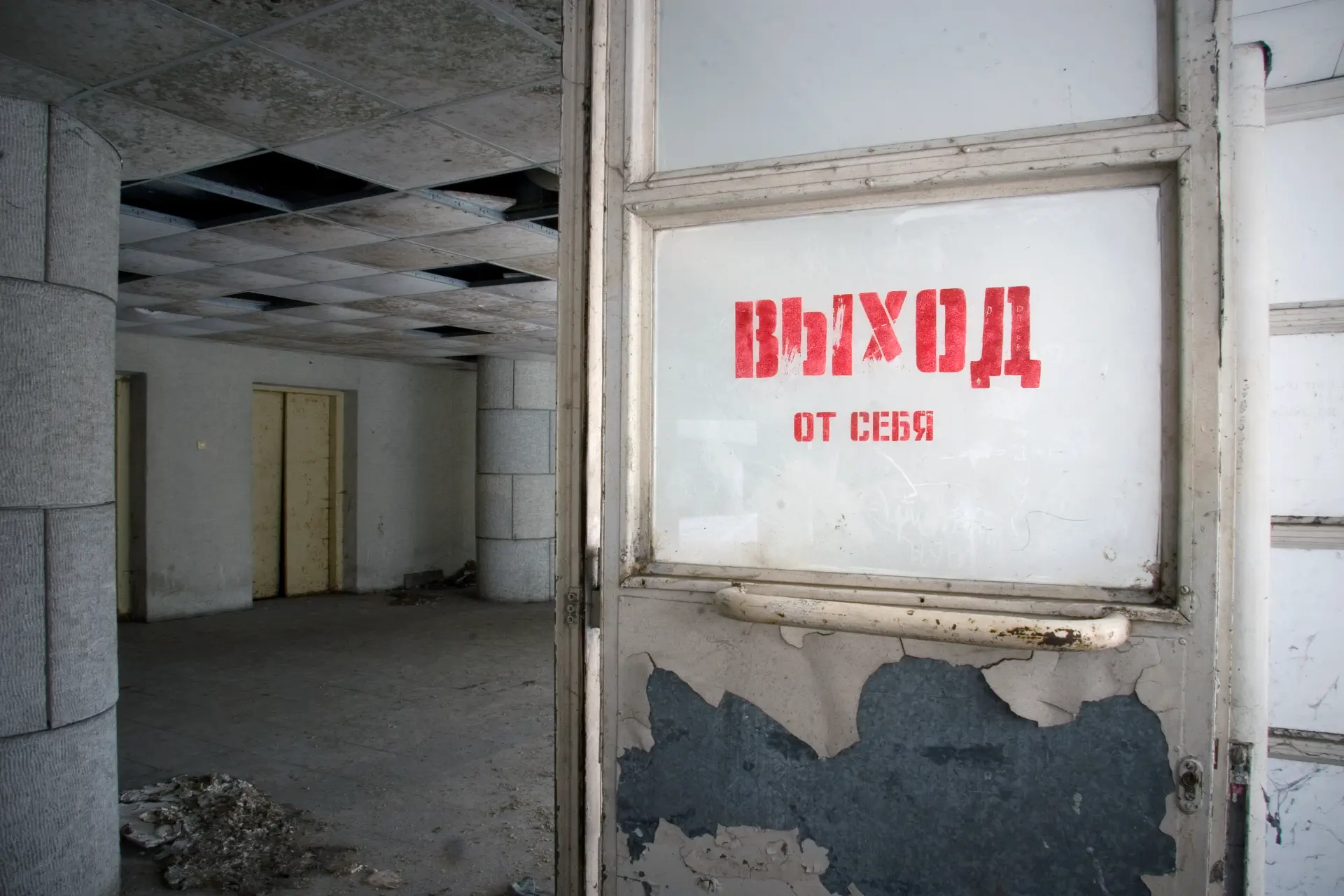 The door of a ruined building with an inscription in Russian: "Exit".